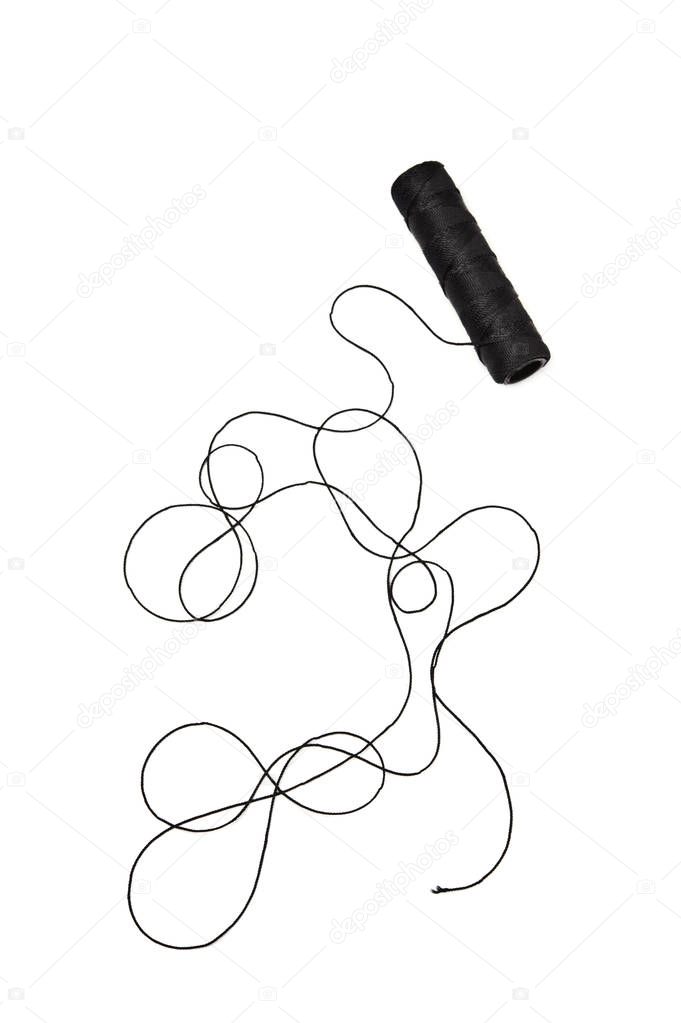 Spool and tangled black thread isolated on white background.