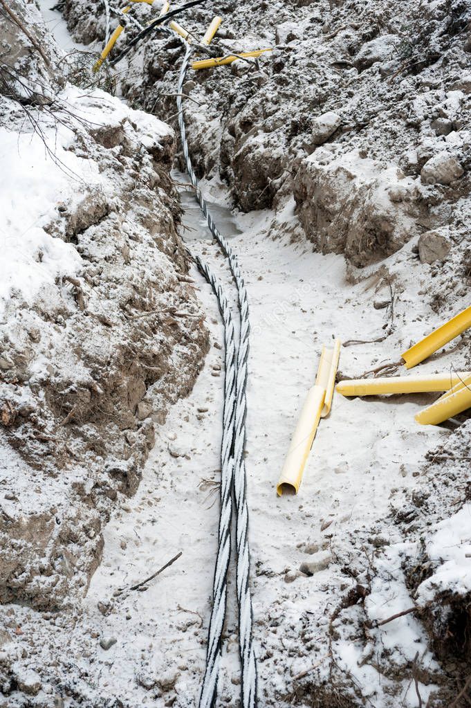 Laying a fiber optic and electricity cables in the frozen ground