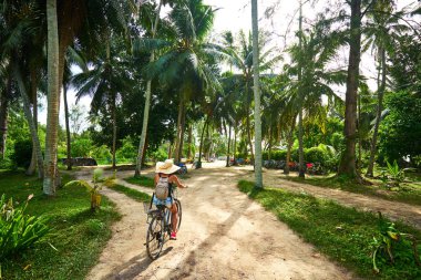 Bisikletli bir kadın vanilya tarlalarını, dique adasını geçiyor.