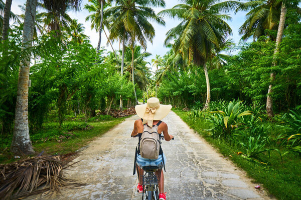 woman on a bicycle crosses vanilla plantations, dique island, se