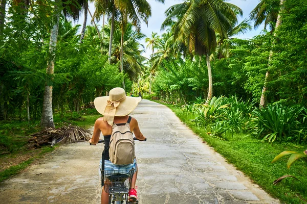 Bisikletli bir kadın vanilya tarlalarını, dique adasını geçiyor.