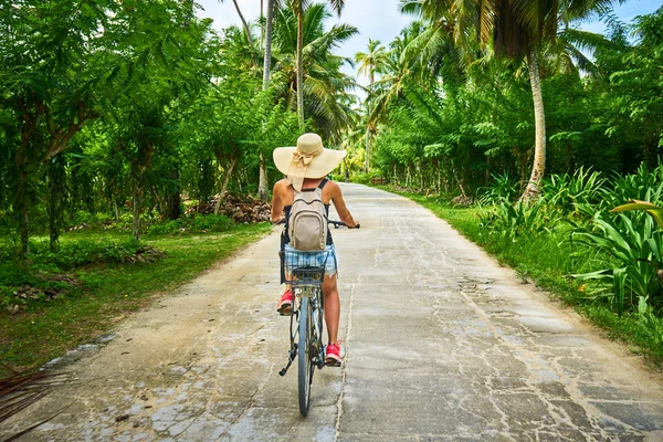 Bisikletli bir kadın vanilya tarlalarını, dique adasını geçiyor.