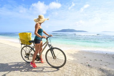 Güzel plajlarda bisiklet süren kadın turist, La Digue Adası.