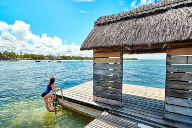 Güzel kadın iskelede güzel kısrak kumsalının yanında, Mauritius adasında dinleniyor.