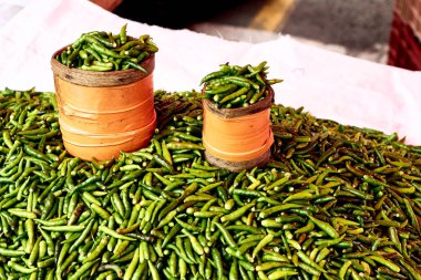 La Runion açık hava pazarında taze yeşil biberlerle dolu bir tezgah, adanın zengin aşçılık mirasını ve taze ürün kültürünü ön plana çıkarıyor.