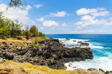 Grand Bois, La Runion 'ın volkanik kıyı şeridi, kara volkanik kayalara çarpan dalgalar, engebeli ve dramatik bir kıyı manzarası yaratır.