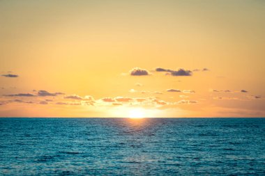 La Runion 'daki Saint-Gilles gölünün üzerinde canlı bir günbatımı, sakin suya yansıyan altın renkler. Sakin ve pitoresk bir tropikal manzara.