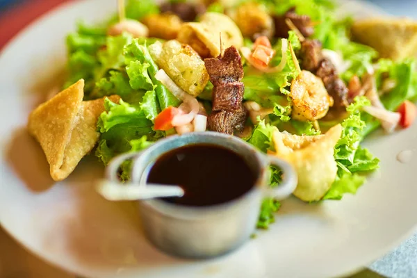 Canlı bir Creole tapas tabağı, çıtır karides kızartması, sulu biftek şişleri, samosalar ve ferahlatıcı yeşil salata. Egzotik yemek, paylaşım tabakları ve Creole tatları için mükemmel bir tema.