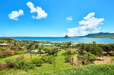 Madagaskar, Diego Suarez Körfezi 'nin manzaralı manzarası, turkuaz suların üzerinde yükselen ikonik Sugarloaf dağı ve kıyı boyunca geleneksel evler. Seyahat ve doğa fotoğrafçılığı için mükemmel bir manzara..