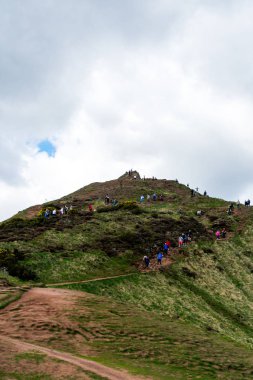 Edinburgh 'da bir dağa yürüyen bir sürü insan bulutlu bir günde
