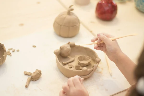 Children make clay. The hands of the child hold the clay. Light room. Clay dishes