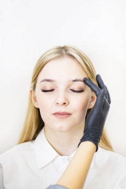 Kadın kozmetolojist güzellik salonunda güzel modellerde kaş düzeltme gerçekleştirir. Kızın yüzü sarışın. Close. Yüz bakımı