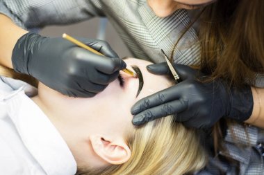 Güzellik uzmanı bir güzellik salonunda güzel bir model kaş düzeltme gerçekleştirir. Kız sarışın. Yüz bakımı. Kına boyama