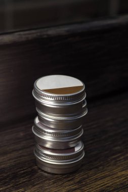 Koyu bir arka plan üzerinde kaşları boyamak için kına kavanoz. Dört kalay paketi üst üste uzanır. Close