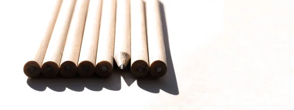 8 pencils are on the table in bright daylight. Natural unpainted wood. Eco-friendly materials. Not like everyone else — Stock Photo, Image