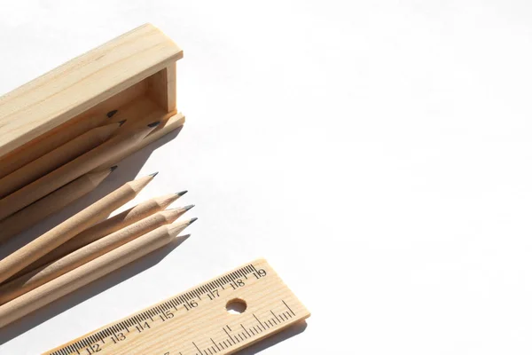 Pencil case and pencils are lying on the table in bright daylight. Natural unpainted wood. Eco-friendly materials — Stock Photo, Image