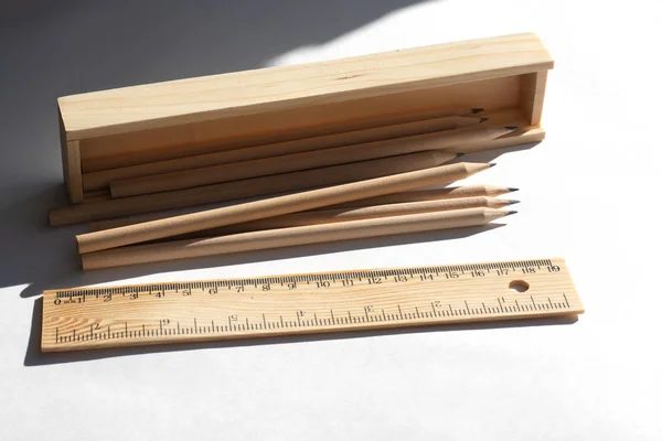 Pencil case and pencils are lying on the table in bright daylight. Natural unpainted wood. Eco-friendly materials — Stock Photo, Image