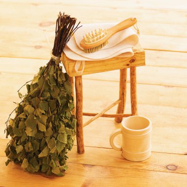 Saunada şımartılmak ve dinlenmek. Buhar odası, ahşap mobilyalar, banyo süpürgesi ve kupadaki su için aksesuarlar.