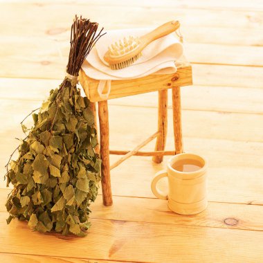 Saunada şımartılmak ve dinlenmek. Buhar odası, ahşap mobilyalar, banyo süpürgesi ve kupadaki su için aksesuarlar.
