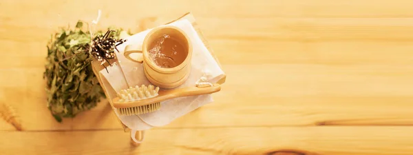 Mimpar e relaxar na sauna. Acessórios para uma sala de vapor, móveis de madeira, uma vassoura de banho e água em uma caneca . — Fotografia de Stock