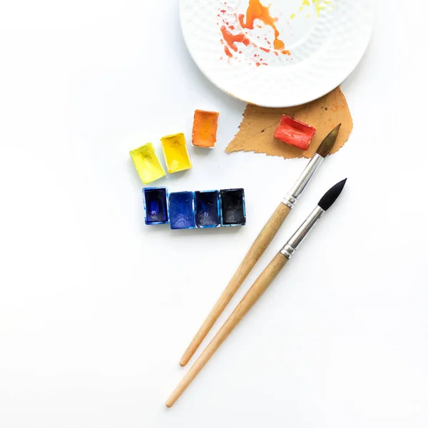 Счастливой осени. Рабочее место с тарелкой, ручками и акварелью, плоская композиция . — стоковое фото