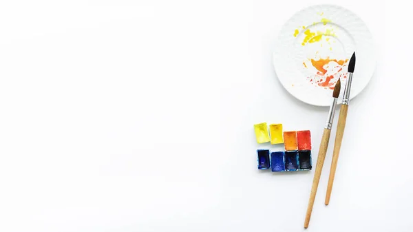 Aquarel, penselen en palet op een witte achtergrond, bovenaanzicht. Hobby 's en goed humeur — Stockfoto