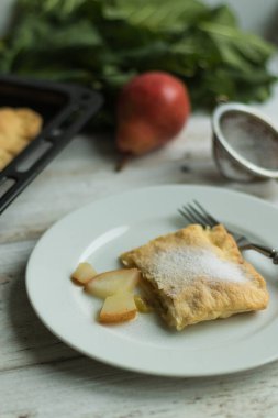 Kız pastanın bir kısmını tabağa koyar. Fırın tepsisindeki tatlı sağlıklı hamur işleri. Pudra serpiştirilmiş kek.