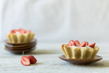 Tereyağlı tart ve beyaz ahşap arka planda taze çilek..