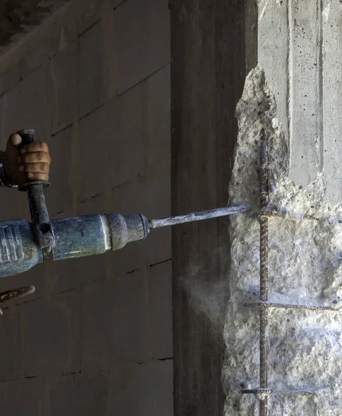 Construction worker with an electric demolisher hammer. Demolition of degraded concrete reinforced concrete pile for subsequent reconstruction of the structure