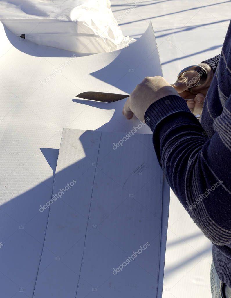 Worker cuts PVC sheet with a scissors