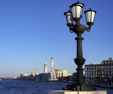 Bari, İtalya - 8 Nisan 2018: karakteristik lamba direği ön planda ve arka planda deniz kıyısına monte edilmiş dönme dolap