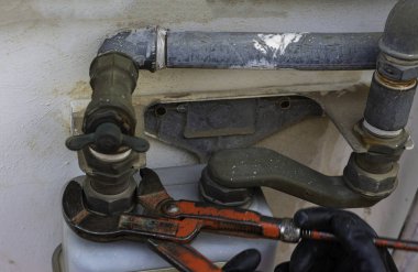 Kaliperli işçi, boru ve gaz sayacı arasındaki montajı söküyor. Seçici odaklama