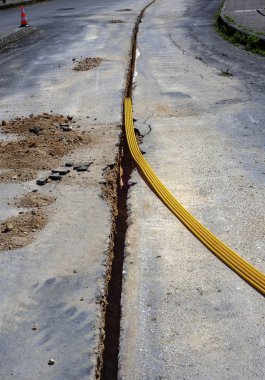 Telekomünikasyon dağıtım ağı için fiber optik kablolar çalıştırmak için gömülü plastik kanallar için kısıtlı bir bölüm kazmak.