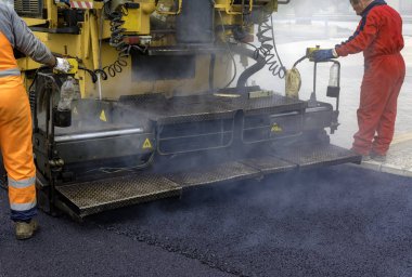 Asfalt paver ile inşaat sırasında 160 derecenin üzerindeki sıcaklıklara ısıtılan. Yol özel ekipman yolu döşeme.