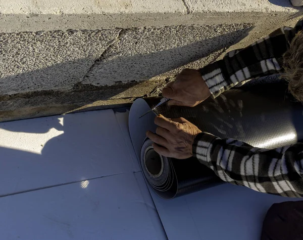 Worker with a heat gun is welding PVC sheets for waterproofing a terrace. Selective focus