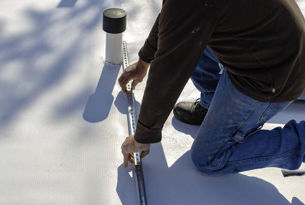 Worker with a heat gun is welding PVC sheets for waterproofing a terrace. Selective focus