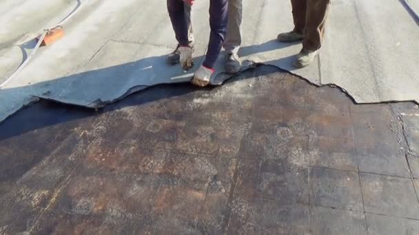 Workers remove the damaged bituminous layer from the flat roof of a building — Stock Footage Workers Remove Damaged Bituminous Layer Flat Roof Building Royalty Free Stock Video