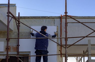 Cephe ısı yalıtımı metre ile çalışan adam.
