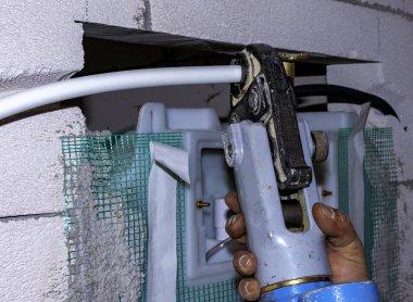 Çok katmanlı boru presleyicili işçi, bağlantı parçalarının metal burçlarını monte ediyor