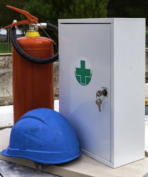 Safety equipment on a construction site: fire extinguisher, helmet, sanitary kit