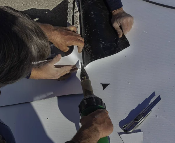 Worker with a heat gun is welding PVC sheets for waterproofing a terrace. Selective focus