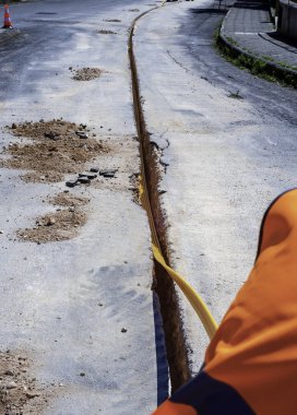 Telekomünikasyon dağıtım ağı için fiber optik kablolar çalıştırmak için gömülü plastik kanallar için kısıtlı bir bölüm kazmak.