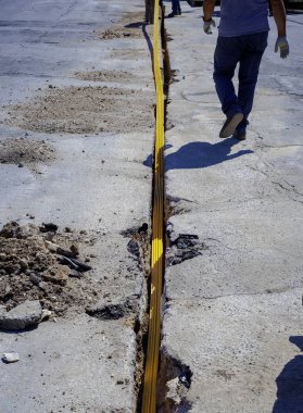 Telekomünikasyon dağıtım ağı için fiber optik kablolar çalıştırmak için gömülü plastik kanallar için kısıtlı bir bölüm kazmak.