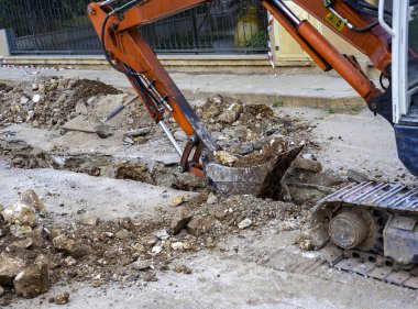 Fiber optik telekomünikasyon kablo dağıtım ağı üretmek için kıvrımlı plastik kablo kanallarını gömecek dar bir bölümle yapılan kazı..