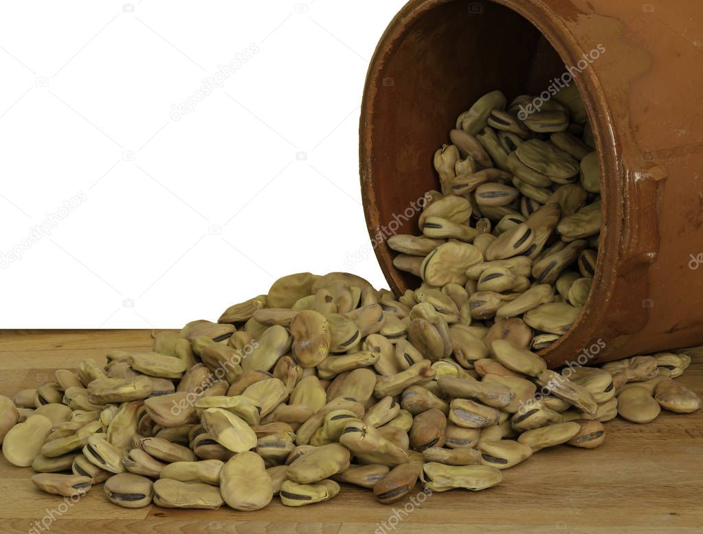 Broad beans not shelled in an earthenware bowl arranged on a kitchen countertop