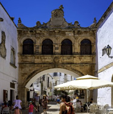 Ostuni, İtalya - 24 Haziran 2018: Turistler Puglia'nın Ostuni kentindeki katedral meydanının hoş cazibesini gözlemliyor. İtalya