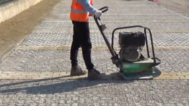 İşçiler, yatakları içindeki blokları sıkıştırmak için vibro-sıkıştırıcı plaka kullanıyorlar.