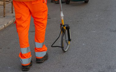 Kanalizasyon sistemindeki hamamböceklerinin defezasyonuna piretroid böcek ilacı sıkılmış. İşçi, kanalizasyon kuyuları arasındaki kilometre sayacıyla mesafeyi ölçer