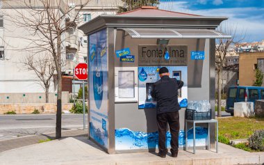 Martina Franca, İtalya - 1 Mart 2016: Vatandaş özel bir şirketin otomatik su dağıtıcısından şişe dolduruyor