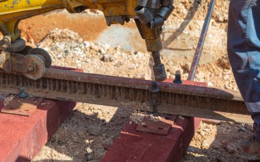 Rayları sürgüleyen demiryolu işçileri. Hafif portatif sondaj makinesi olan detaycı.